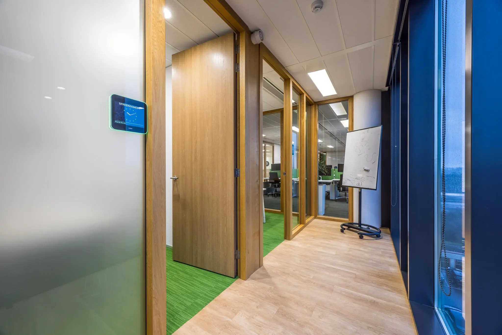 Modern kantoorpand aan de Winthontlaan met open vergaderruimte, glazen wanden en een digitaal reserveringssysteem.