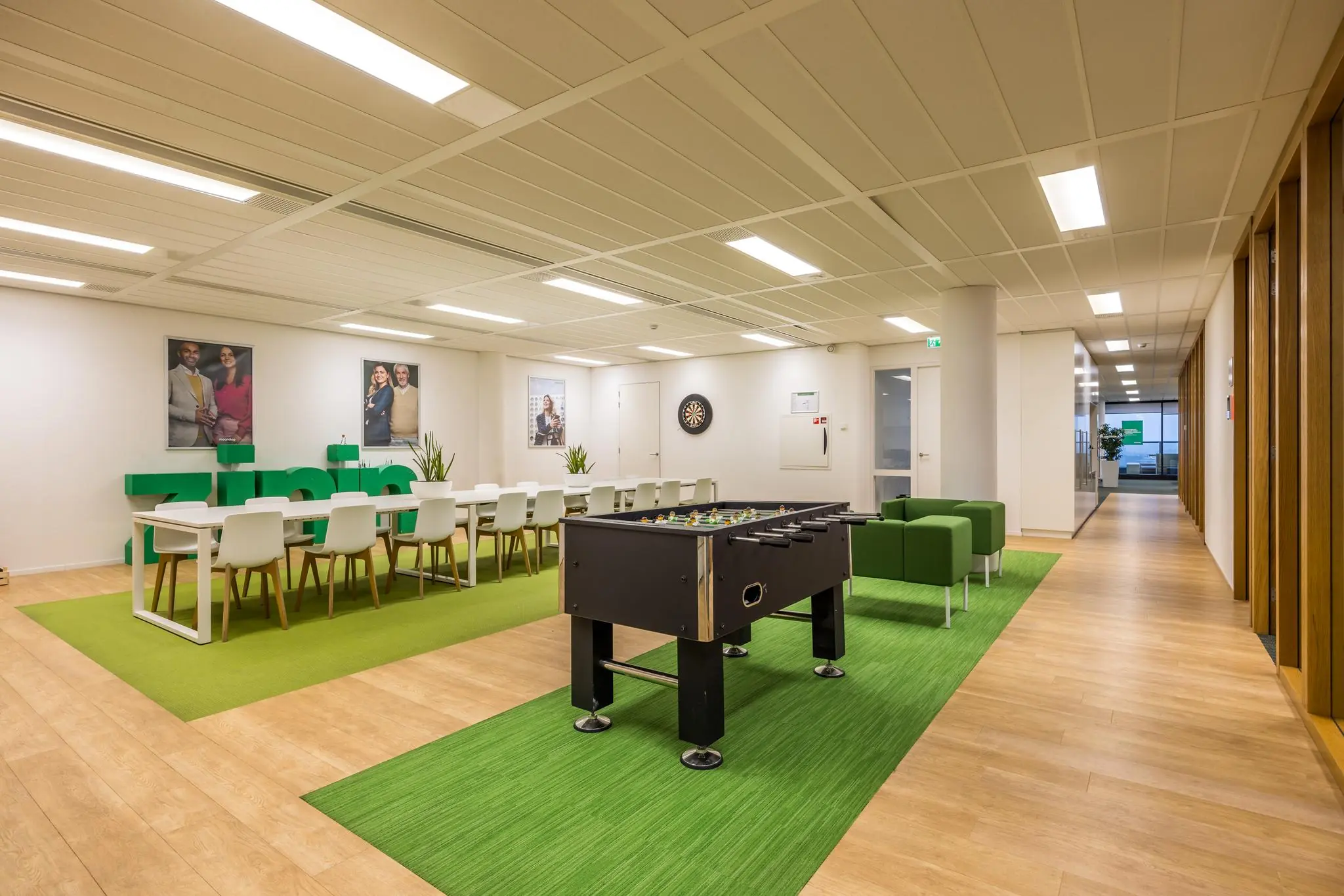 Moderne en open kantoorruimte aan de Winthontlaan met een lange vergadertafel, tafelvoetbaltafel, zithoek en decoratieve elementen in groentinten.