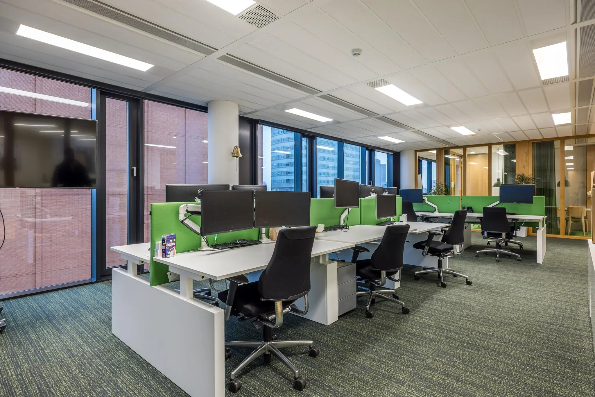 Modern kantoorinterieur aan de Winthontlaan met werkplekken, groene scheidingswanden en uitzicht op hoge kantoorgebouwen.