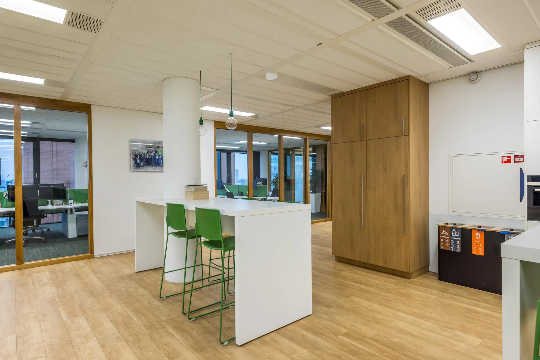 Moderne kantoorruimte aan de Winthontlaan met een kantinetafel, groene stoelen en houten opbergkasten.