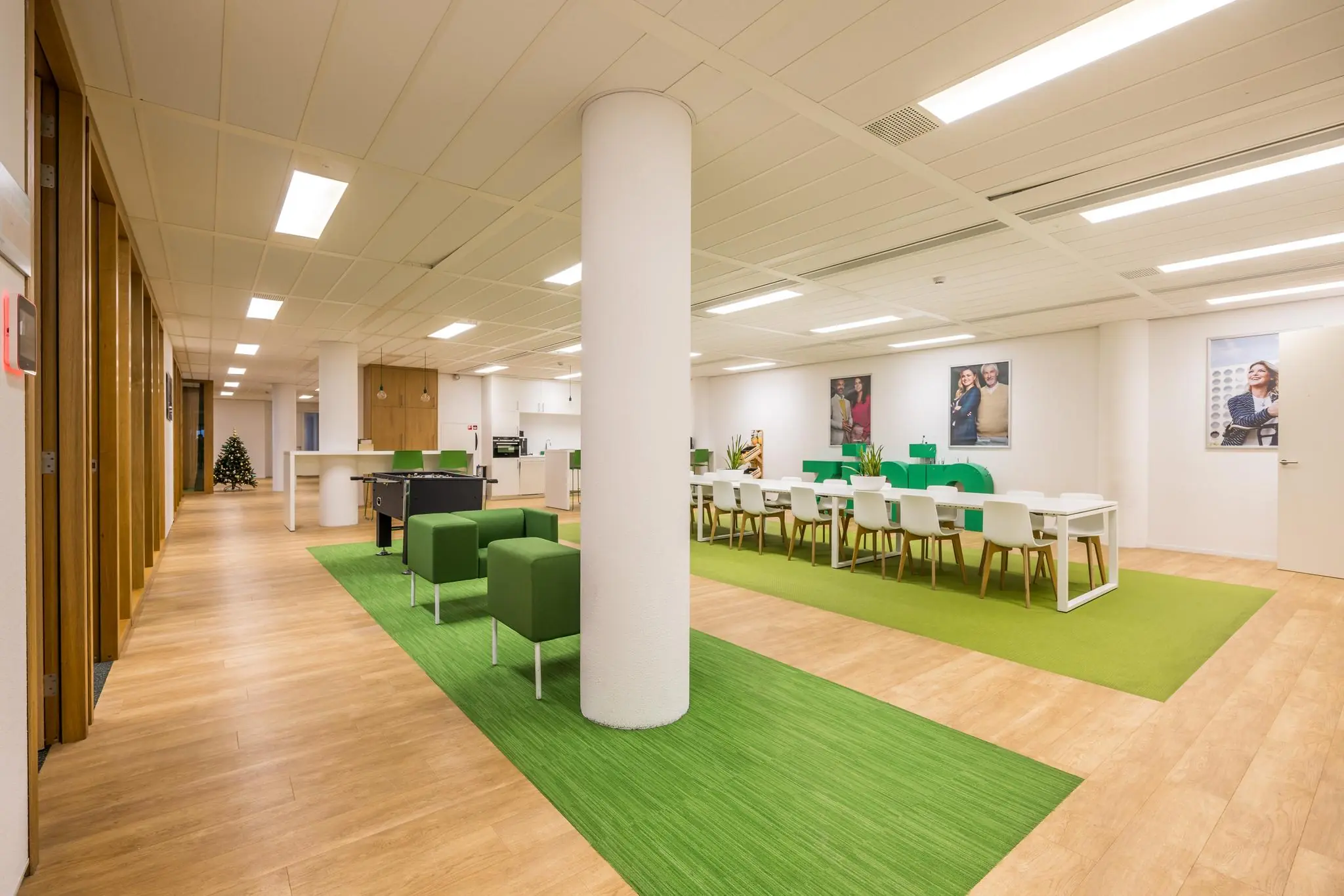 Moderne, open kantoorruimte aan de Winthontlaan met groene accenten, flexwerkplekken, een tafelvoetbaltafel en een gezamenlijke eettafel.