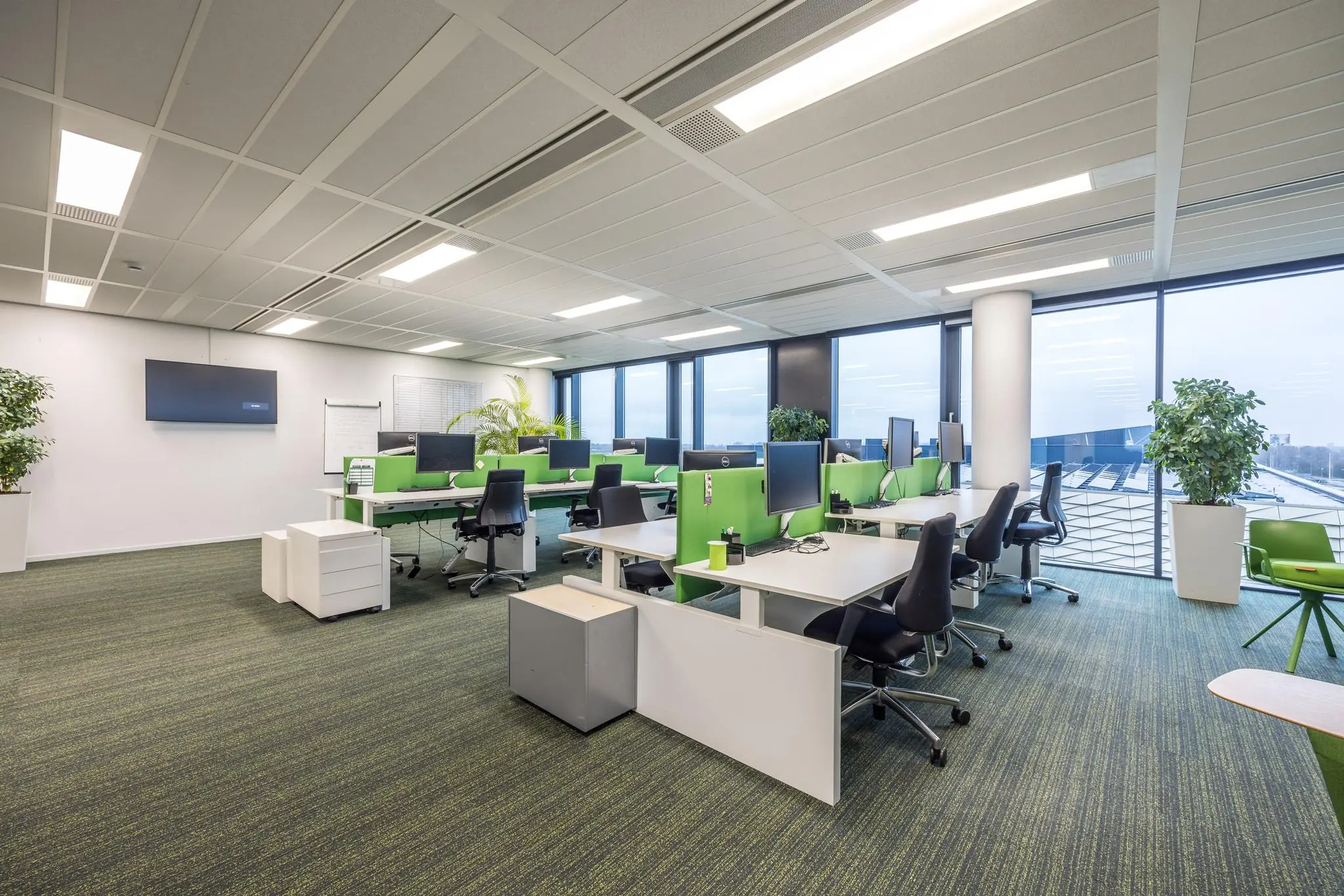 Modern kantoorinterieur aan de Winthontlaan met open werkplekken, groene accenten en grote ramen met uitzicht.