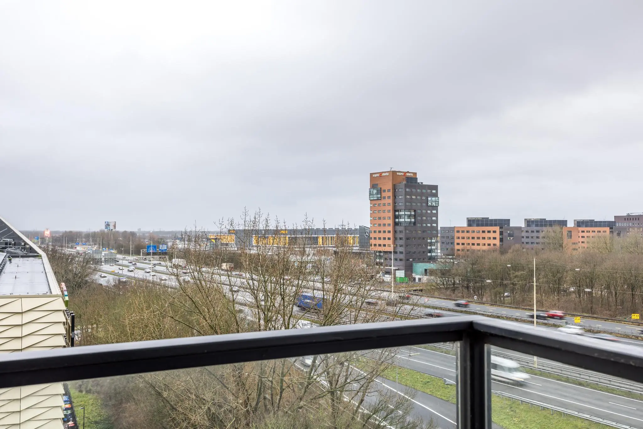 Uitzicht vanaf een balkon op de Winthontlaan in Utrecht met snelwegen, kantoren en het gebouw van Super Office.