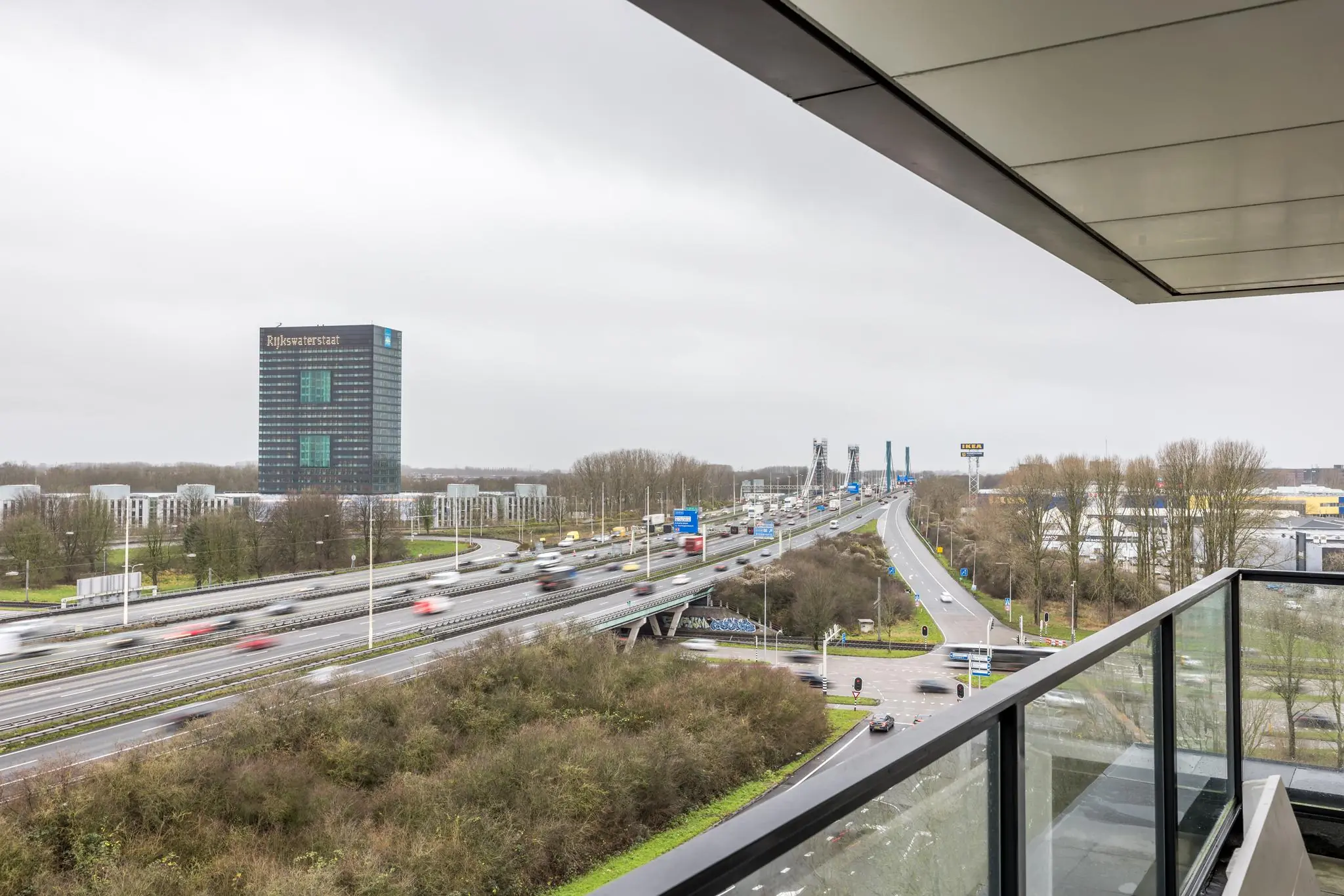 Uitzicht vanaf een balkon op de Winthontlaan met de A12, het Rijkswaterstaat-gebouw en de Prins Clausbrug in Utrecht.