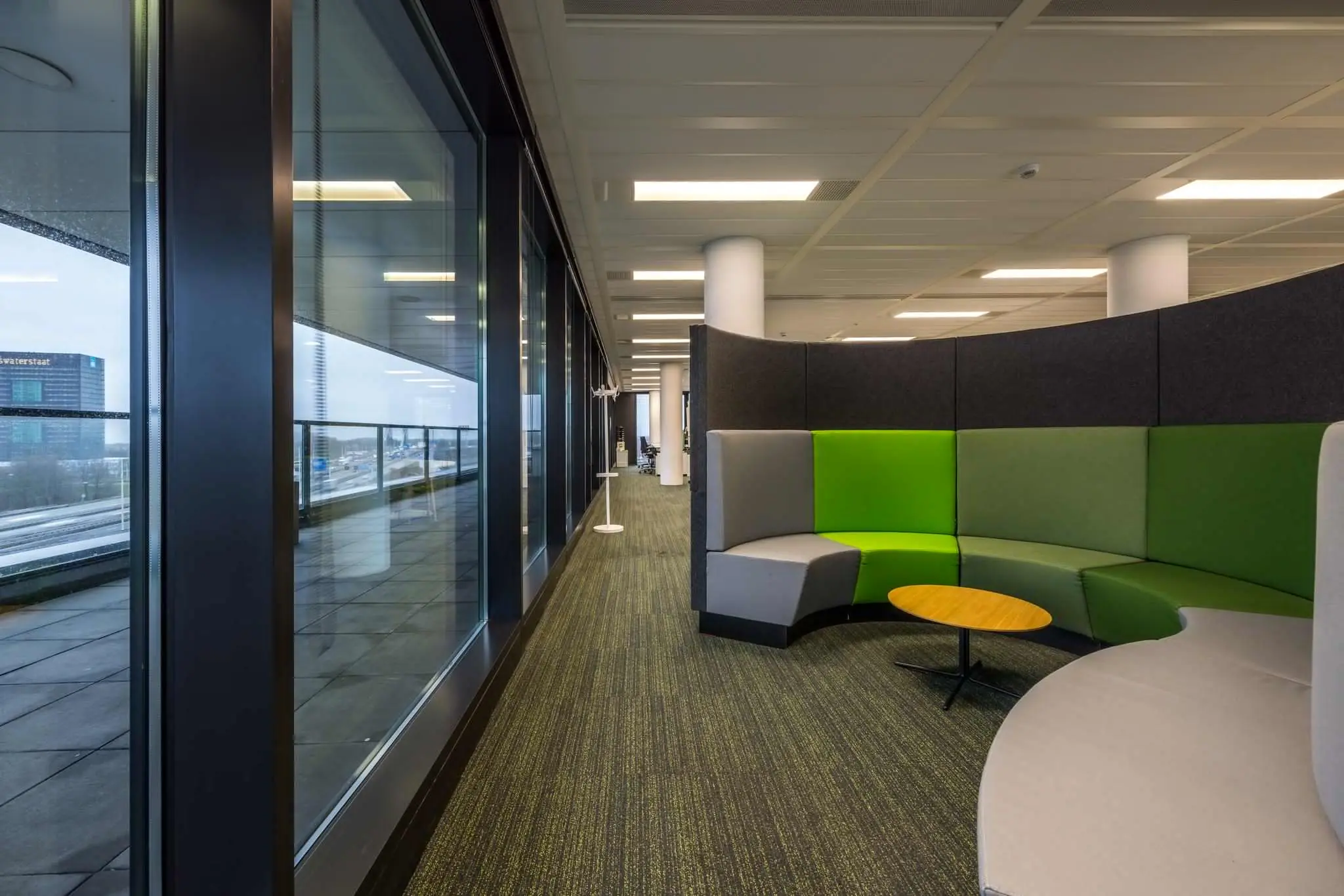 Moderne kantoorruimte aan de Winthontlaan met kleurrijke ronde zithoek en uitzicht op de snelweg.