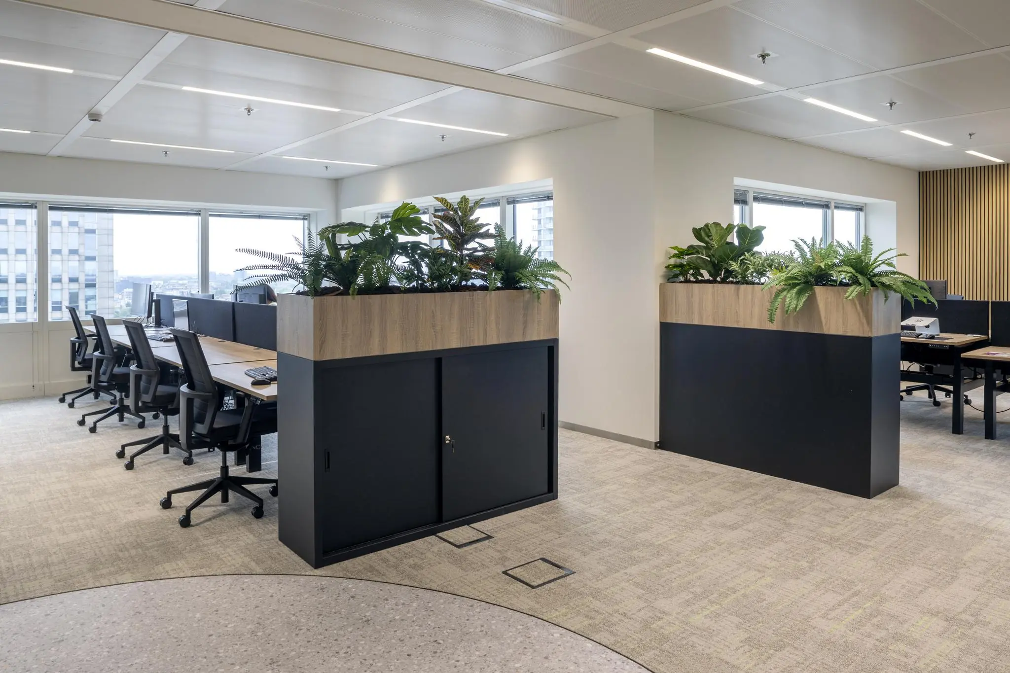 Modern en licht kantoorinterieur op Amstelplein met werkplekken, plantenbakken en grote ramen.