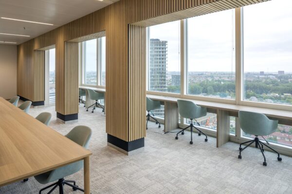 Modern kantoorinterieur aan het Amstelplein met werkplekken langs grote ramen en uitzicht over de stad.