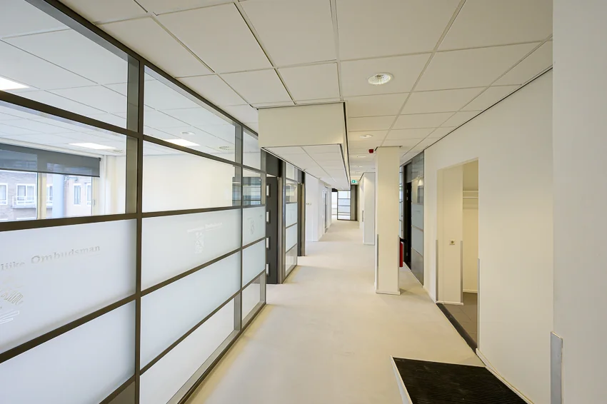 Heldere gang in een modern kantoorgebouw met glazen kantoorwanden van de Nationale Ombudsman.