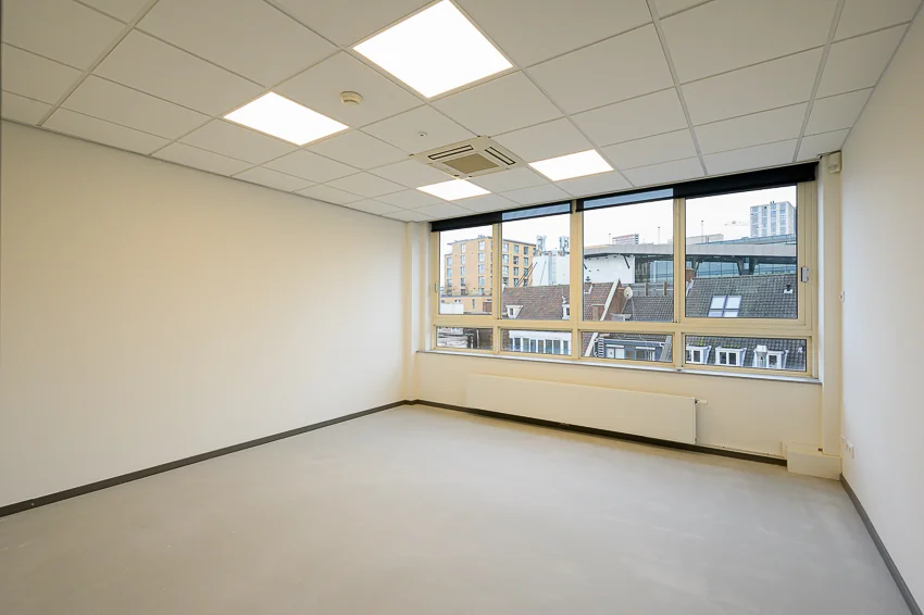 Leeg, modern kantoorpand aan de Meent met grote ramen en uitzicht op omliggende gebouwen.