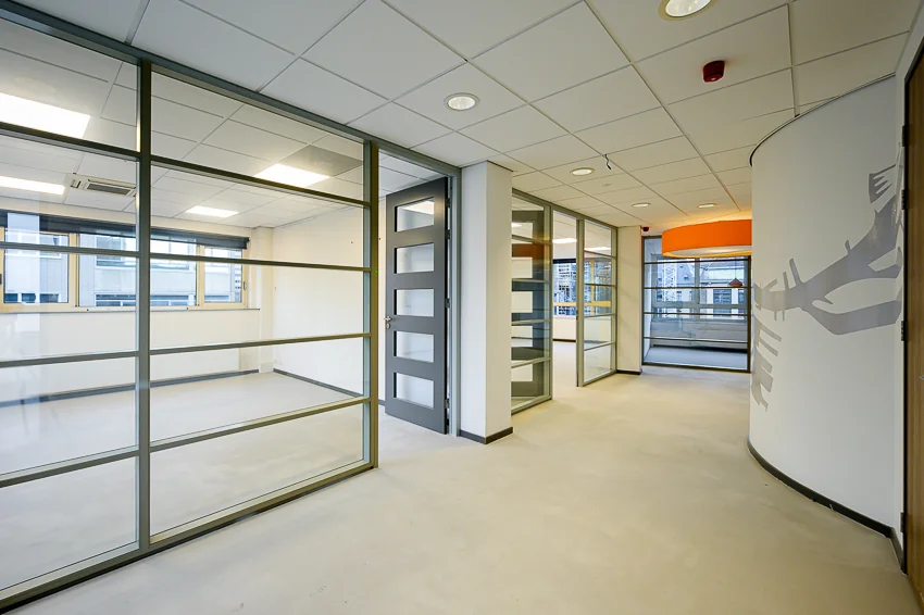 Moderne, lichte kantoorruimte met glazen wanden en een open gang in gebouw Meent.