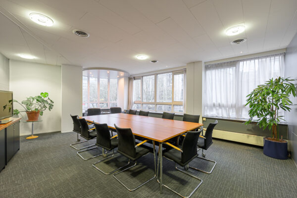 Vergaderruimte Meent met een lange houten tafel, zwarte stoelen en grote ramen die zorgen voor veel daglicht.