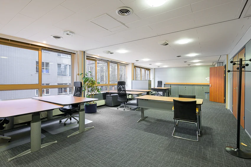 Ruim en licht kantoor met meerdere bureaus, bureaustoelen en grote ramen aan de Meent.
