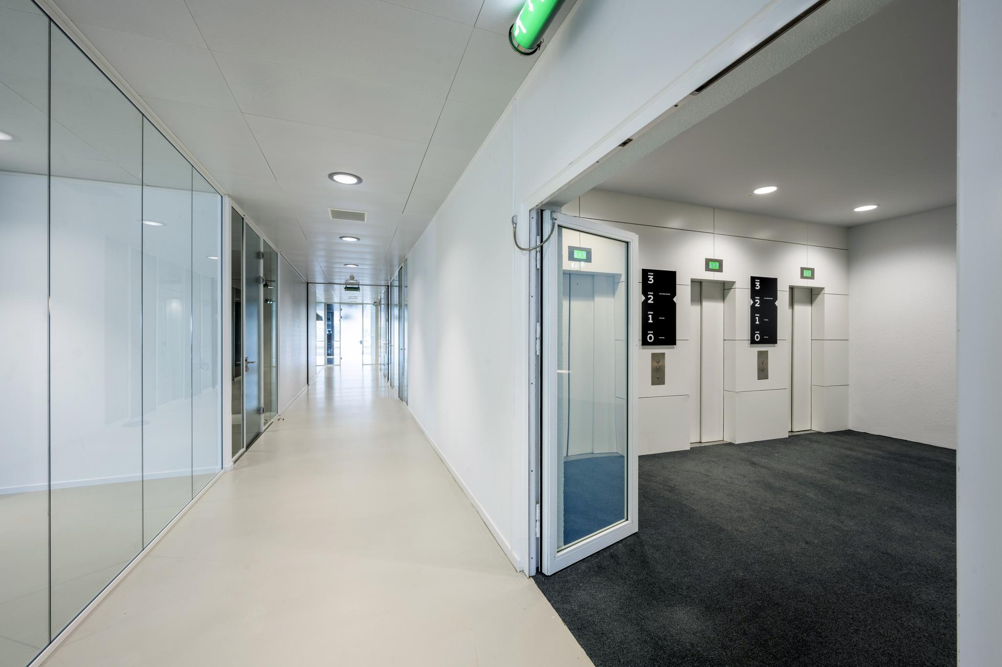 Moderne kantoorhal met glazen wanden en een liftlobby aan de Prof. E.M. Meijerslaan.