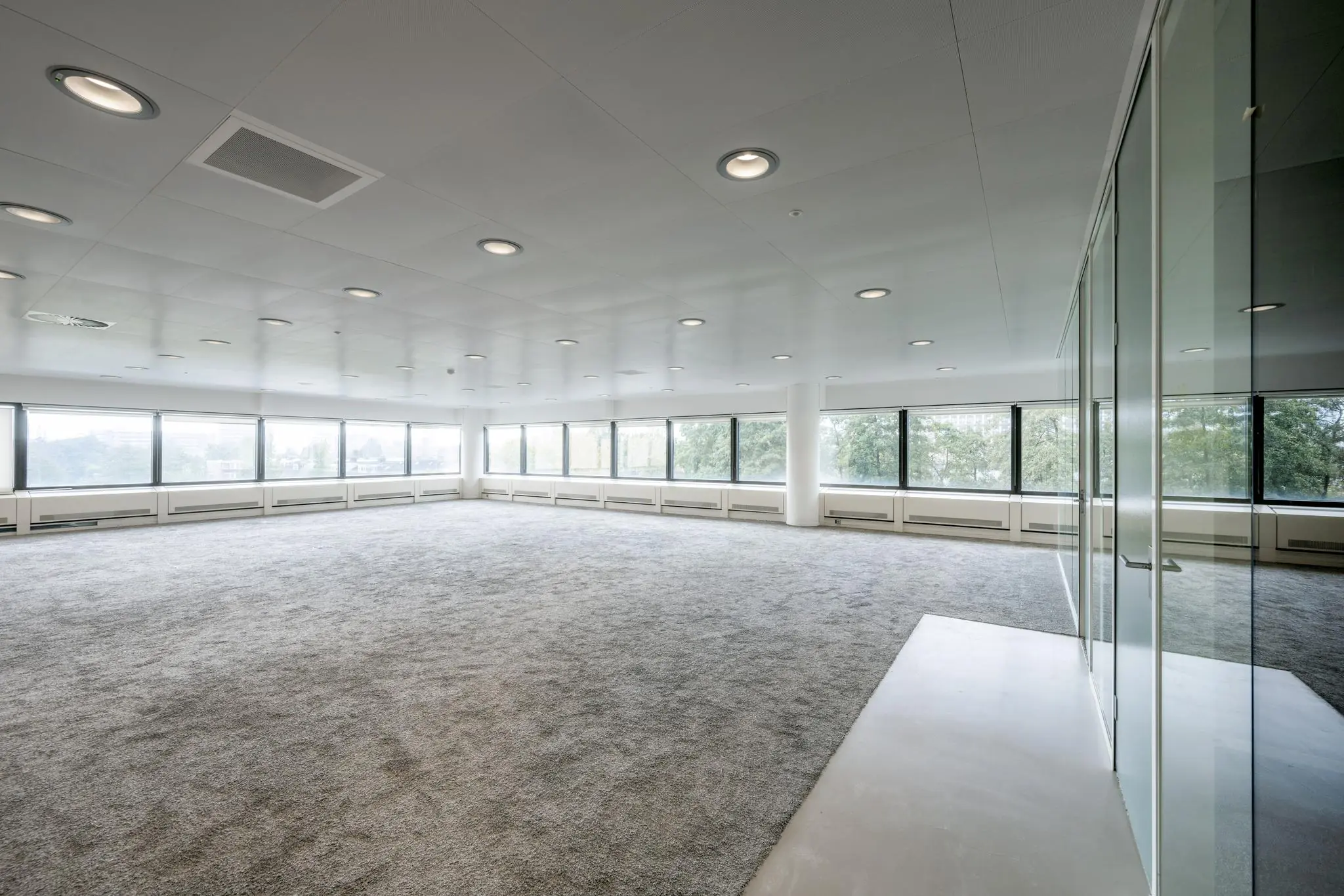 Lichte, lege kantoorruimte met tapijt en grote ramen aan de Prof. E.M. Meijerslaan.