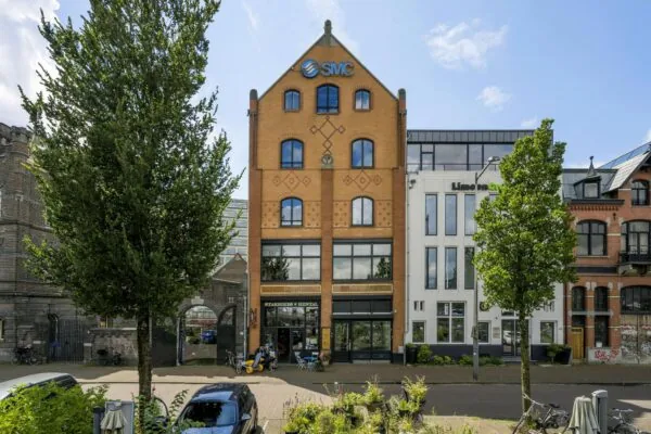 Voorgevel van een karakteristiek kantoorpand aan de De Ruijterkade in Amsterdam met het logo van SMC op de gevel.