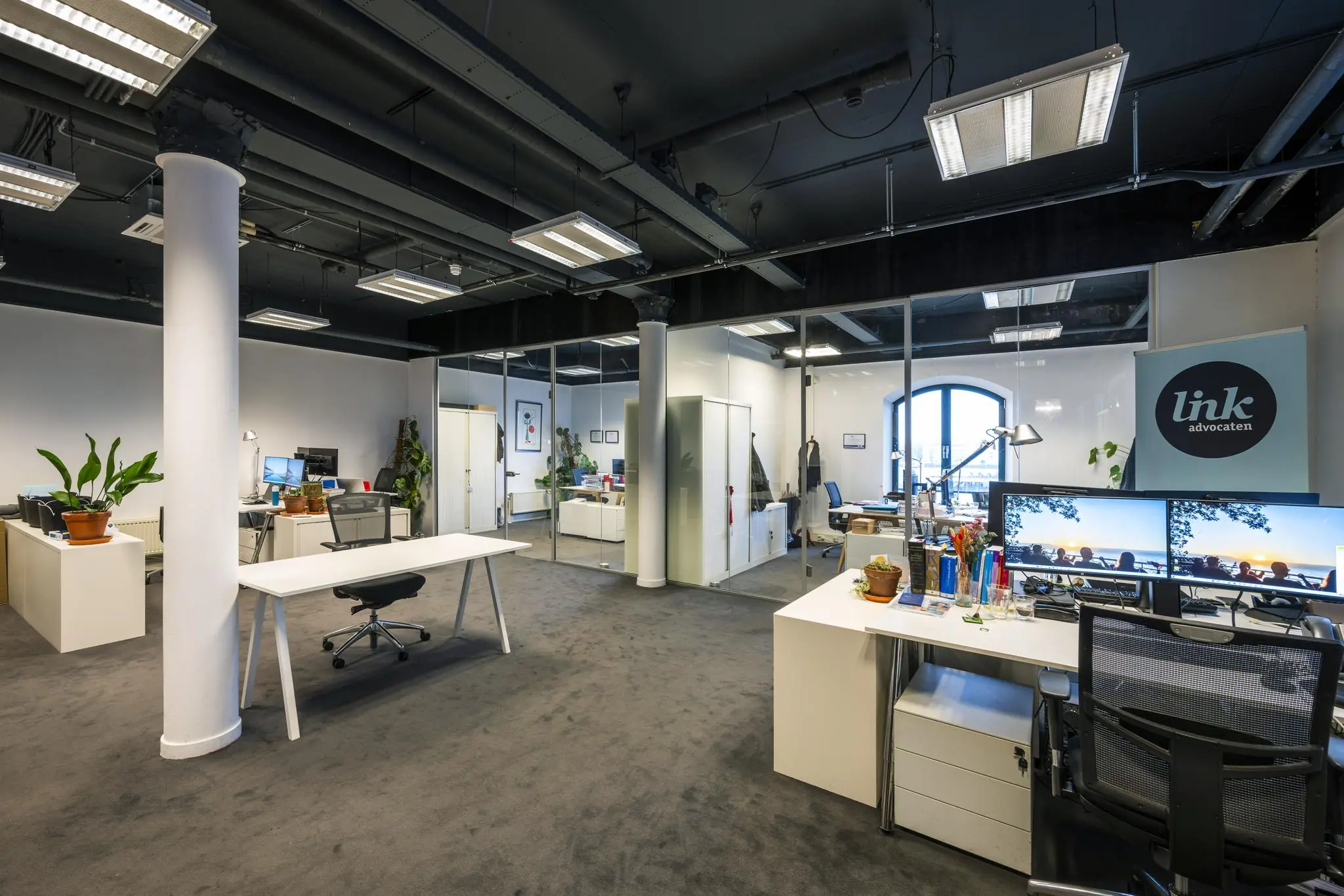 Modern kantoorinterieur van advocatenkantoor Link aan de De Ruijterkade met glazen wanden, bureaus en kantoormeubilair.