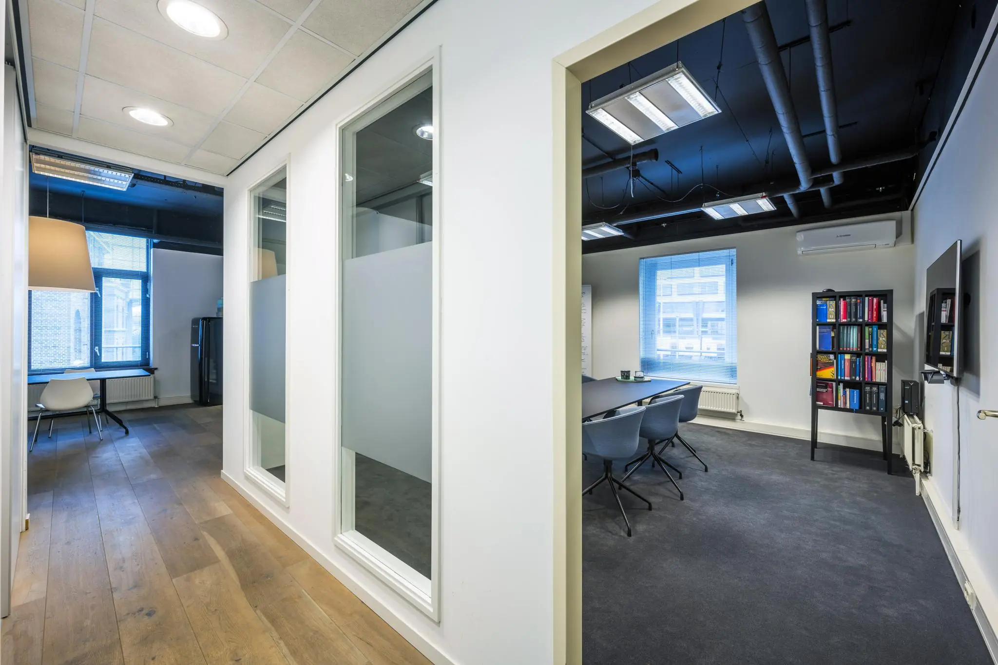 Moderne kantoorruimte aan de De Ruijterkade met vergaderruimte, glazen wanden en houten vloer.