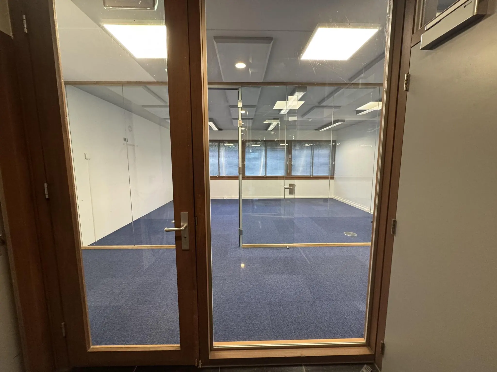 Leeg kantoor met blauwe vloerbedekking en glazen wanden aan de De Ruijterkade.