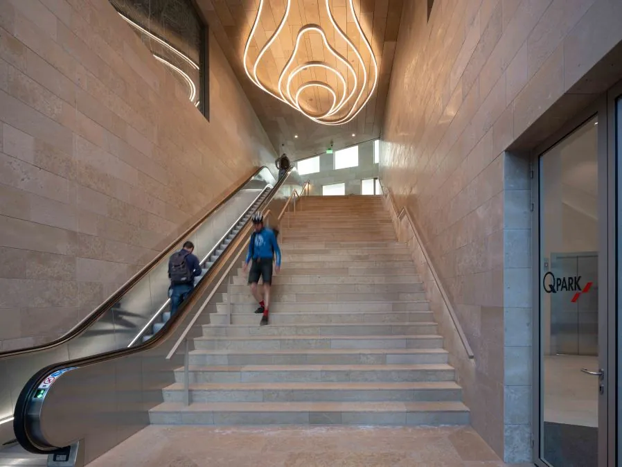 Ingang van Q-Park Beethovenstraat met een brede trap, een roltrap en modern golvend plafondlicht.