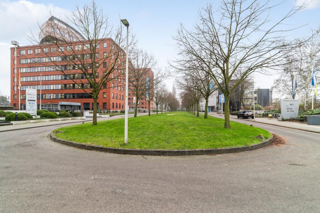 Bedrijventerrein aan de Bordewijklaan met kantoorgebouwen, groene middenstrook en kale bomen aan weerszijden van de weg.