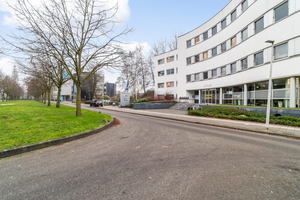 Gebogen straat met bomen en het kantoorgebouw aan de Bordewijklaan in Den Haag.