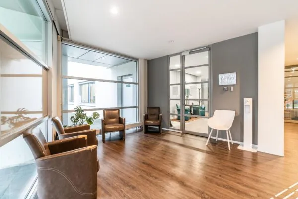 Wachtruimte met stoelen, grote ramen en toegang tot een andere ruimte in een modern kantoorpand aan de Bordewijklaan.