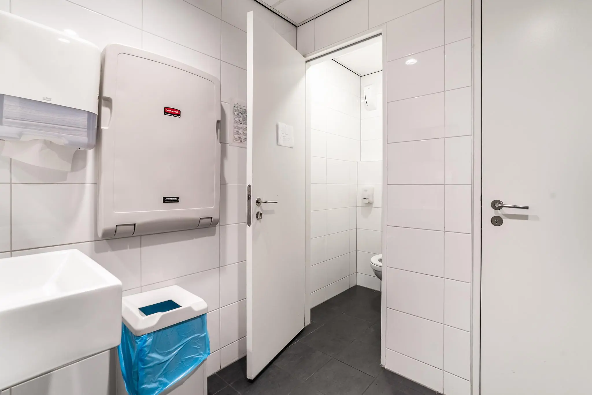 Schone, wit betegelde toiletruimte aan de Bordewijklaan met opklapbare verschoontafel, wasbak en afvalbak.