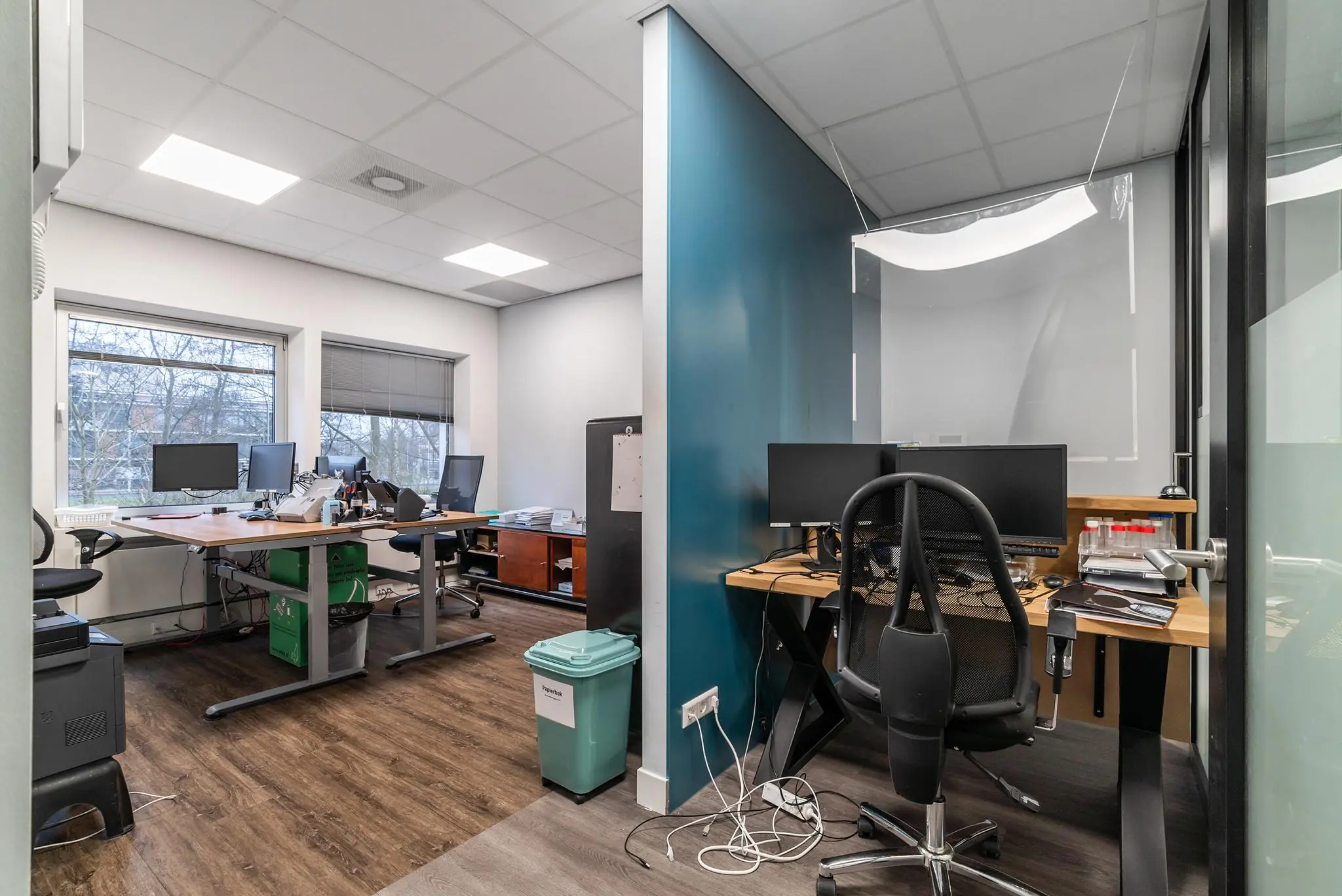 Moderne kantoorruimte aan de Bordewijklaan met meerdere bureaus, computers en een scheidingswand.