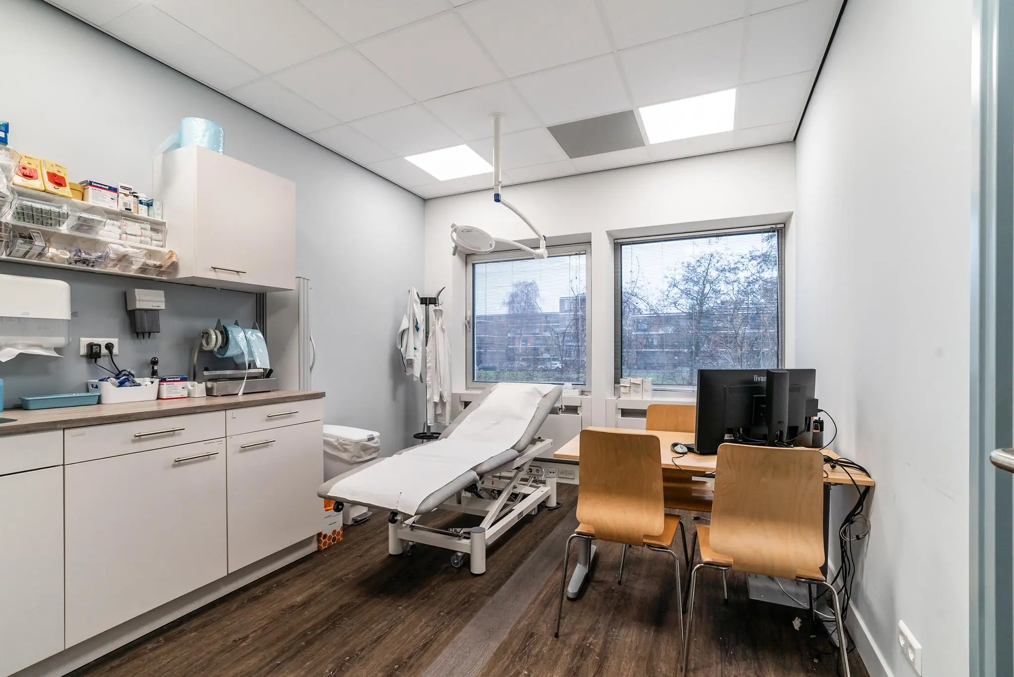 Moderne dokterskamer aan de Bordewijklaan met onderzoekstafel, computerwerkplek en medische benodigdheden.