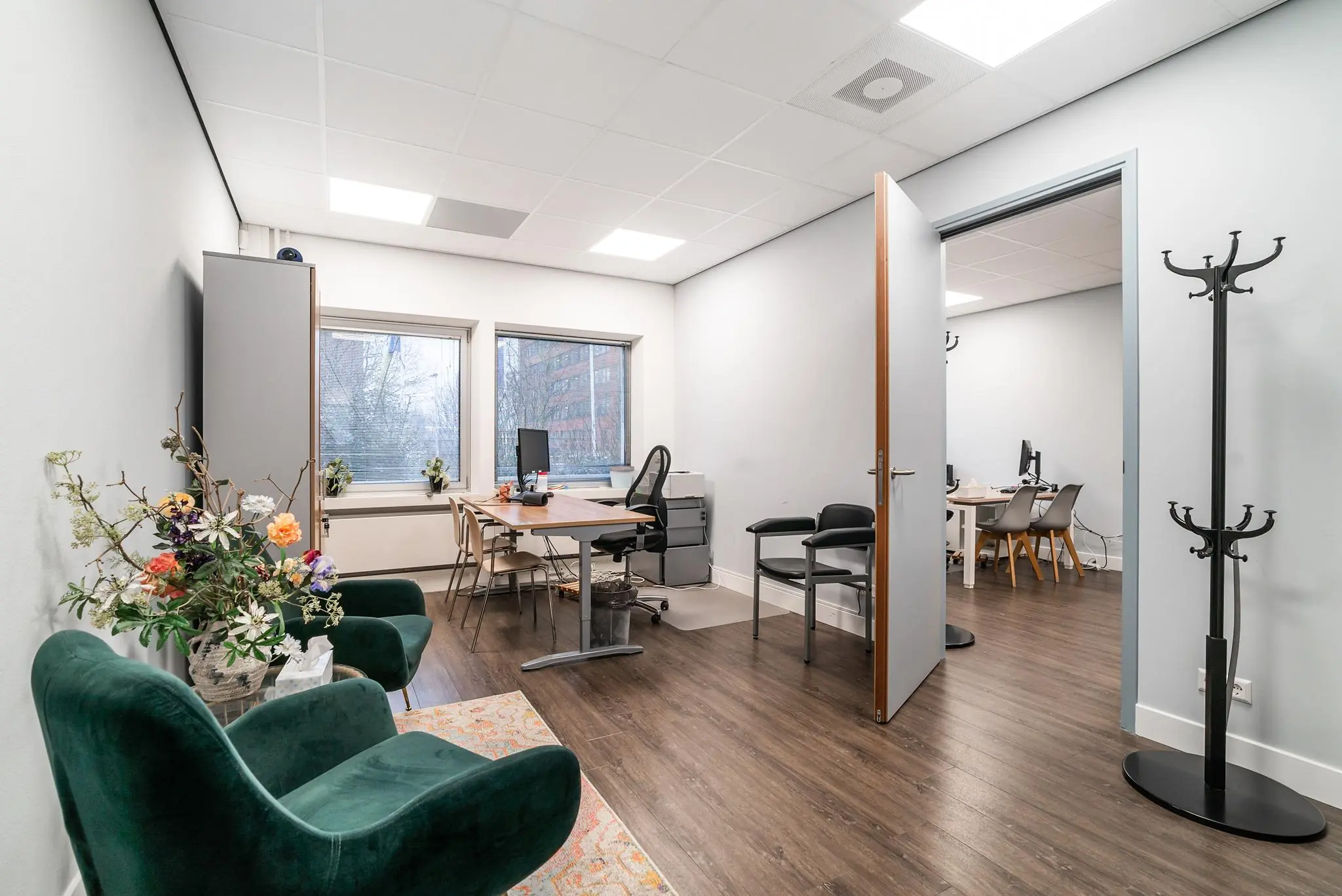Modern kantoor op de Bordewijklaan met twee bureaus, zithoek en open doorgang naar aangrenzende werkruimte.