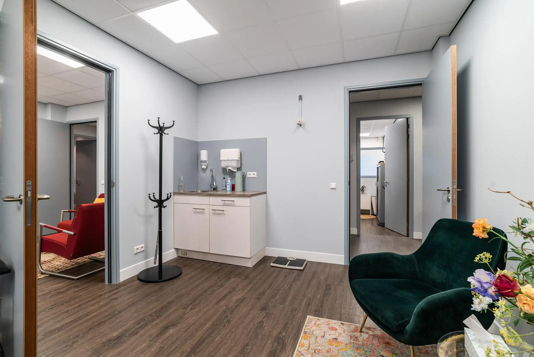 Moderne wachtruimte aan de Bordewijklaan met een zithoek, wastafelmeubel en meerdere deuren naar aangrenzende ruimtes.