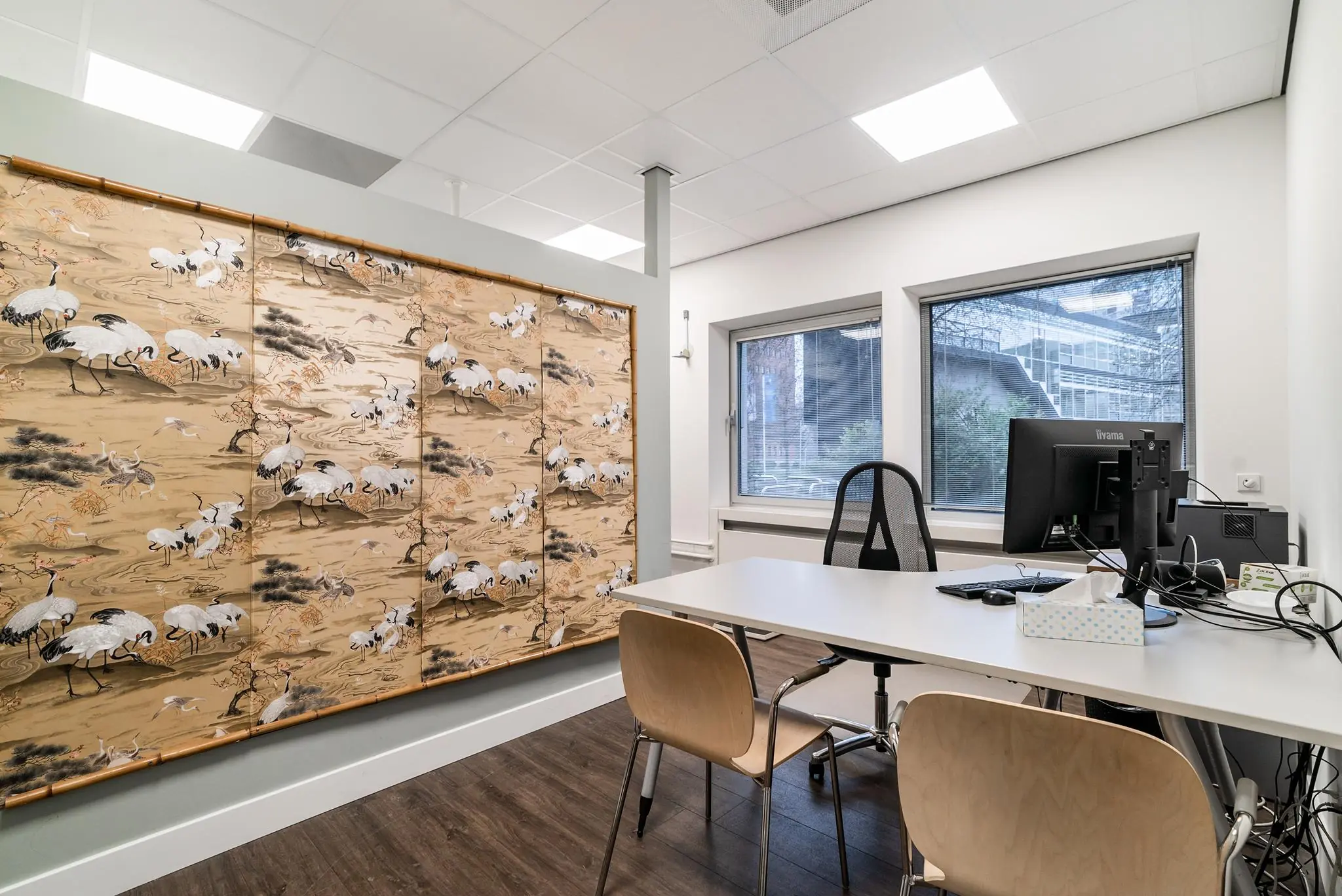 Moderne kantoorruimte aan de Bordewijklaan met twee bureaustoelen, computeropstelling en decoratieve wand met kraanvogeldessin.