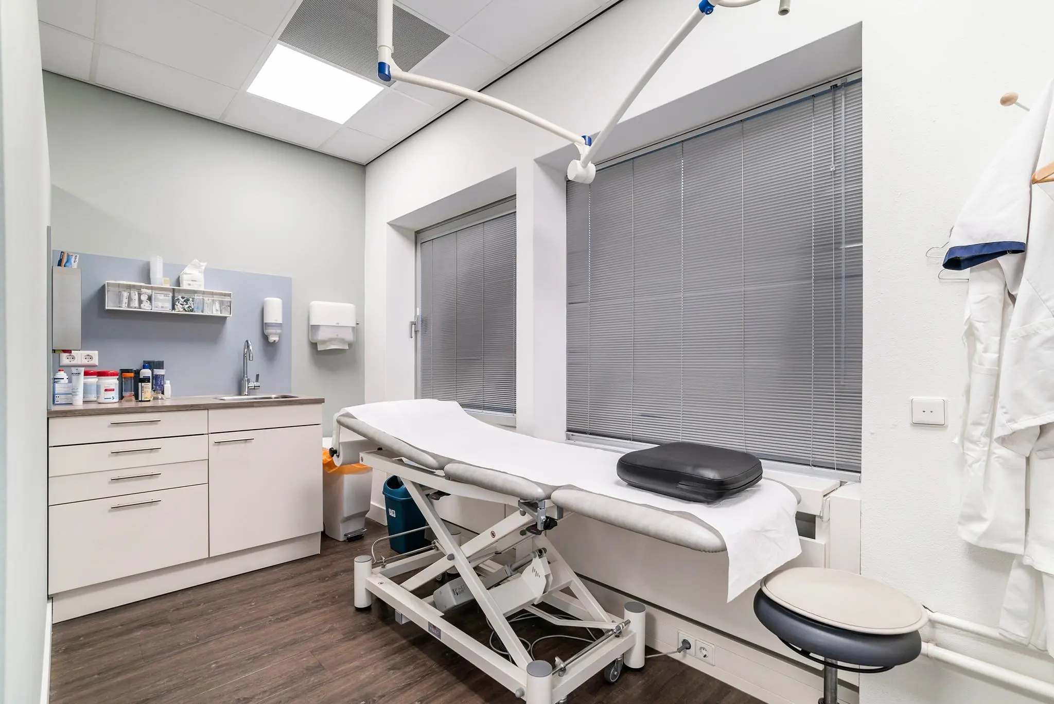 Onderzoeksruimte met een behandelbank, medische apparatuur en opbergkasten aan de Bordewijklaan.