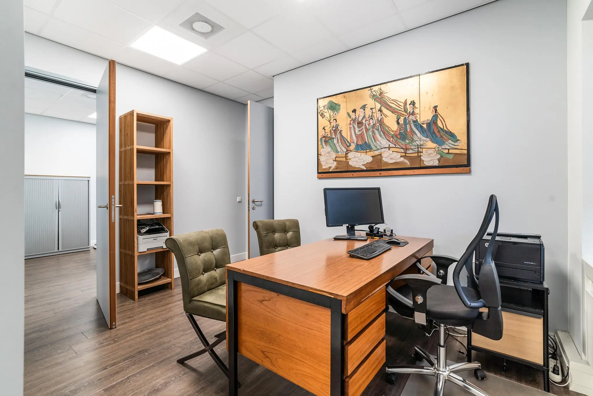 Modern kantoor met houten bureau, twee stoelen en een Aziatisch kunstwerk aan de muur op Bordewijklaan.