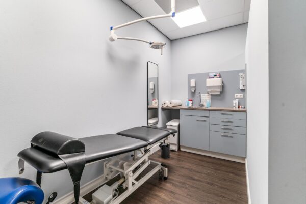 Moderne behandelkamer aan de Bordewijklaan met onderzoekstafel, wastafel en medische apparatuur.