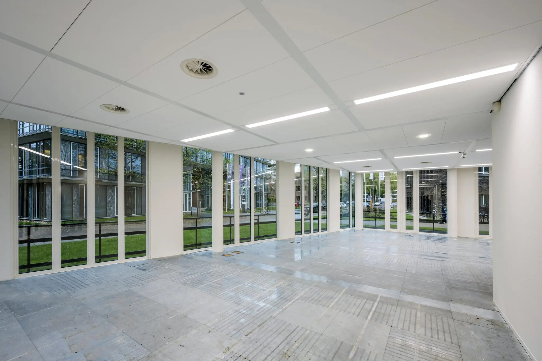 Leeg commercieel hoekpand met grote raampartijen aan de De Cuserstraat in Amsterdam.