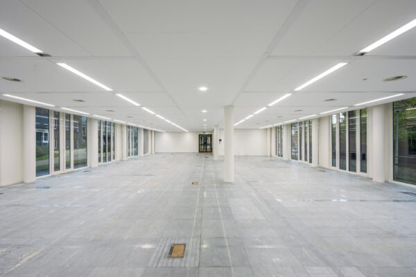 Leeg, modern kantoorpand aan de De Cuserstraat met grote ramen en systeemplafondverlichting.
