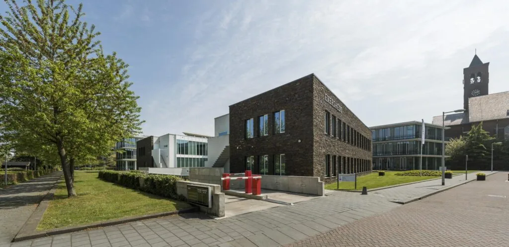 Modern kantoorgebouw aan de De Cuserstraat in Amsterdam, omgeven door groen en andere kantoorpanden.