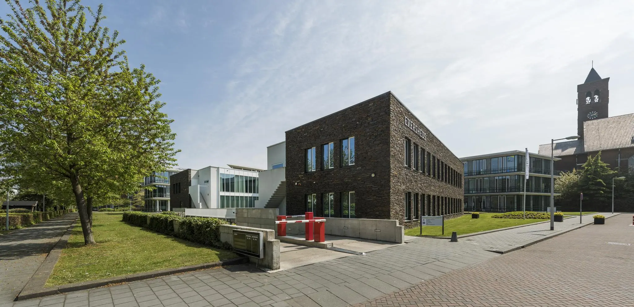 Modern kantoorgebouw aan de De Cuserstraat in Amsterdam, omgeven door groen en andere kantoorpanden.