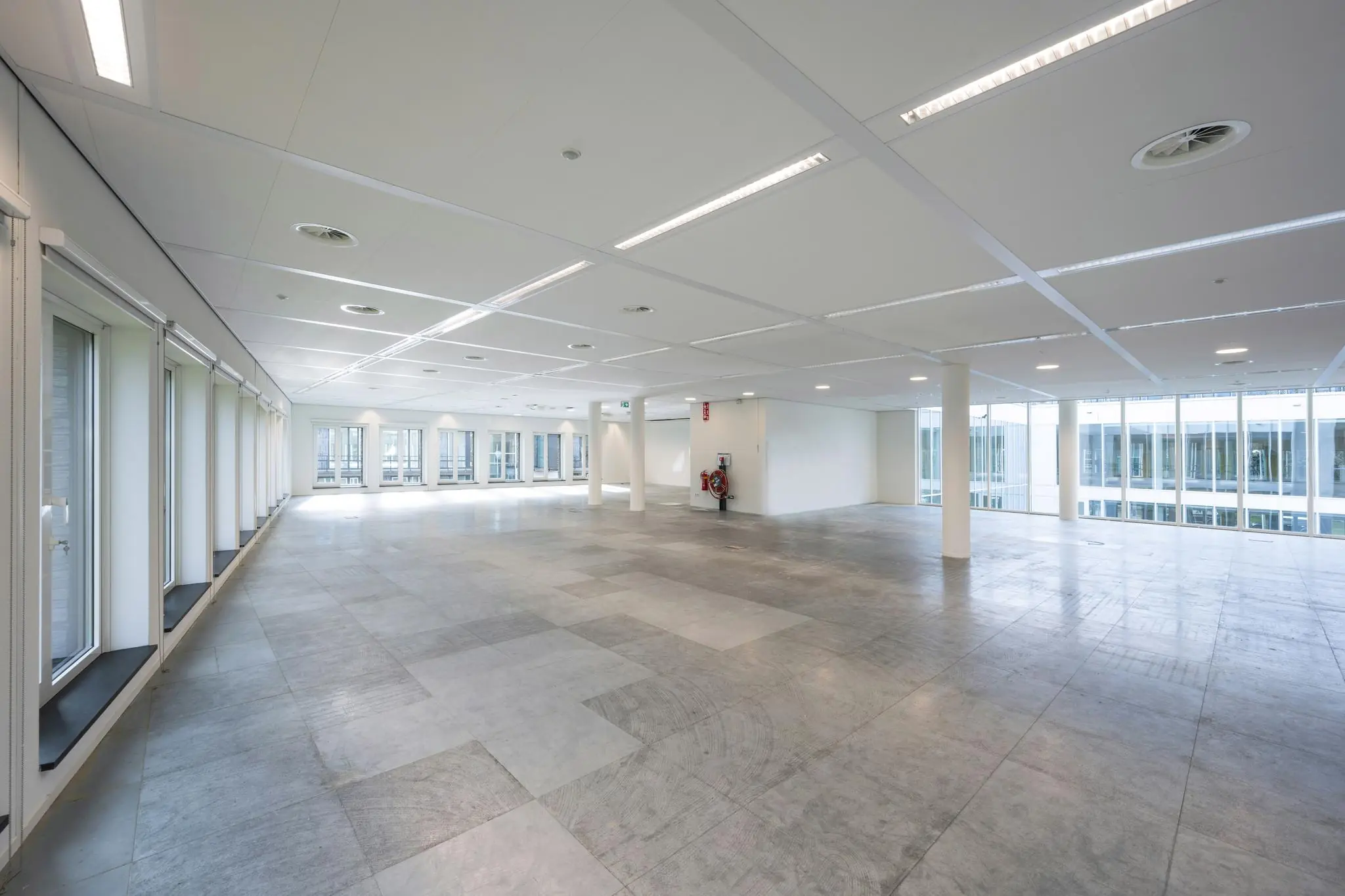 Licht en ruim leeg kantoorpand aan de De Cuserstraat met grote ramen en systeemplafond.