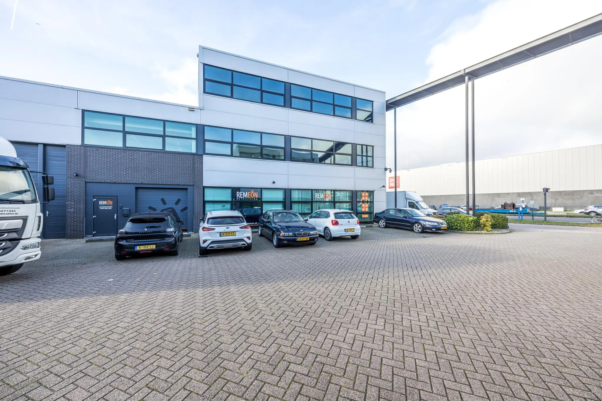 Bedrijfsgebouw aan de Atoomweg met meerdere geparkeerde auto's en het logo van Remeon op de gevel.