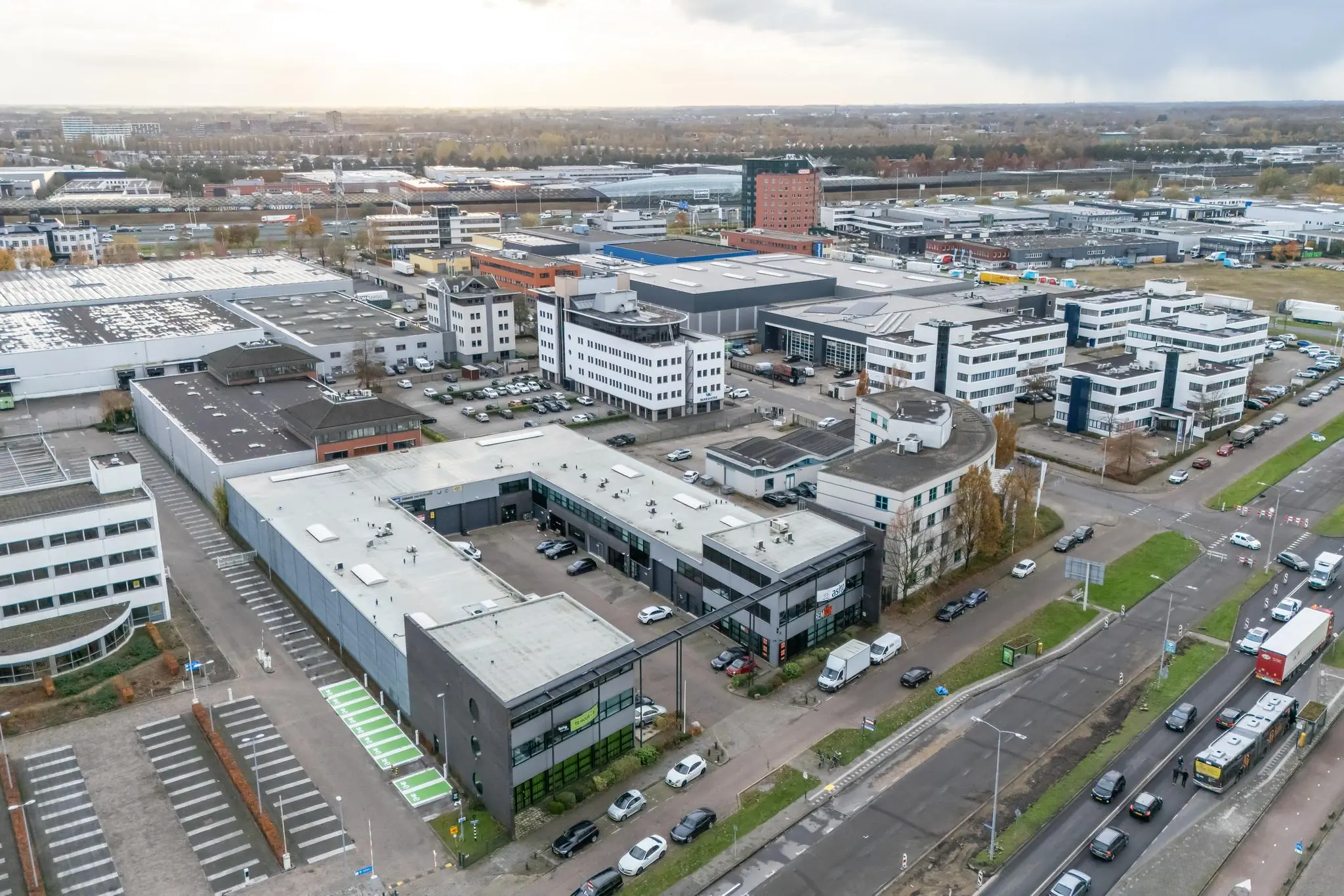 Luchtfoto van een bedrijventerrein aan de Atoomweg in Utrecht, met diverse kantoorgebouwen, parkeerplaatsen en een drukke weg op de voorgrond.