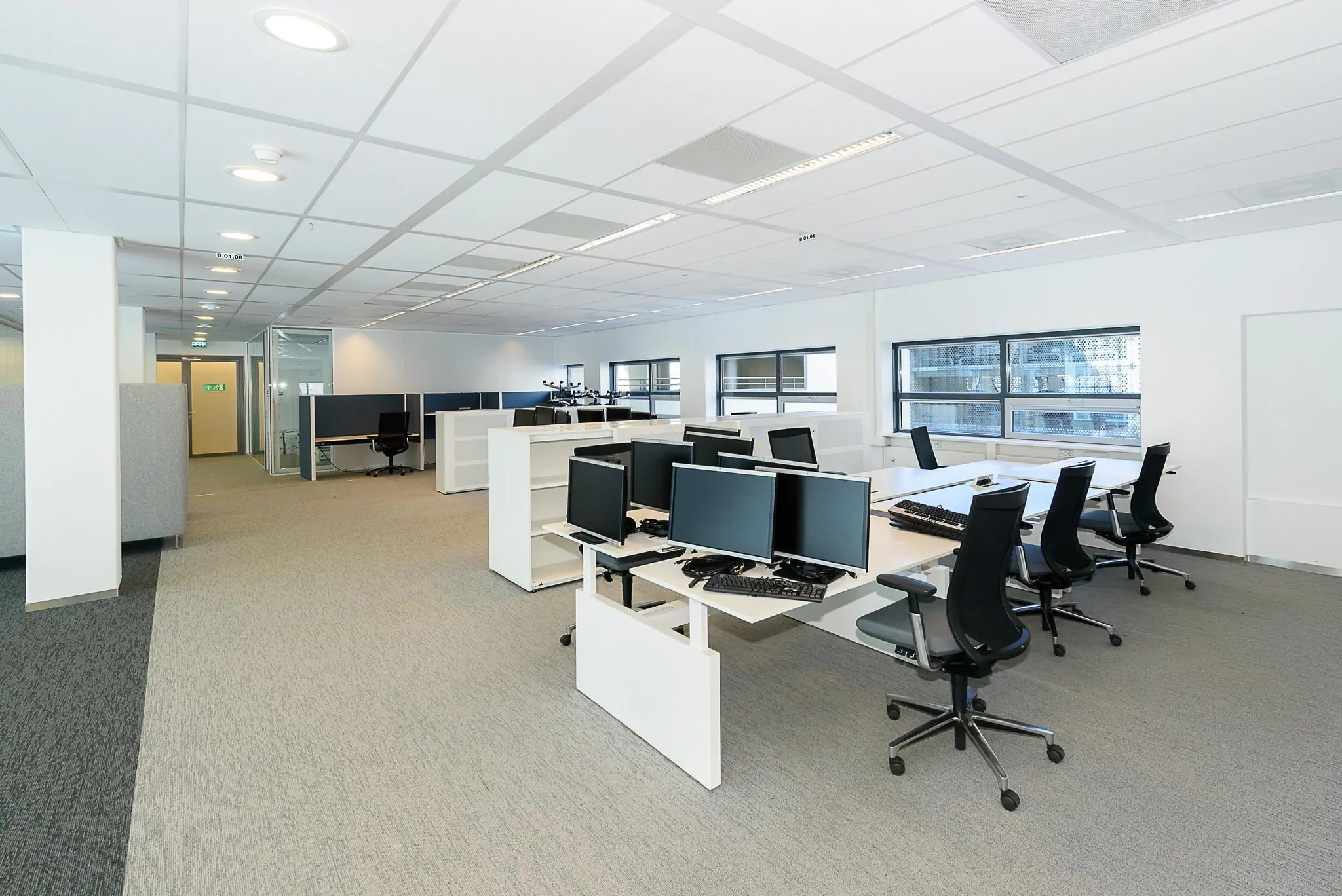 Moderne open kantoorruimte aan het Daalseplein met meerdere werkplekken, bureaustoelen en computers.