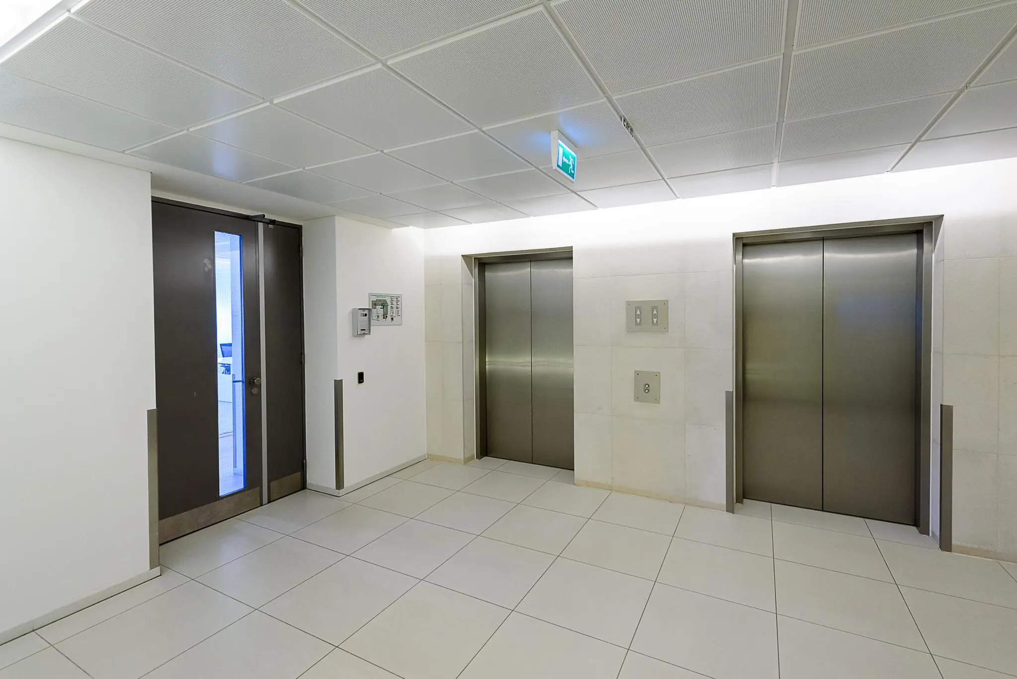 Moderne lifthal in kantoorgebouw Daalseplein met twee gesloten liften en een deur naar kantoorruimte.