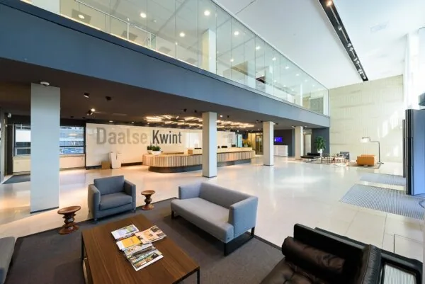 Moderne, ruimtelijke entreehal van het Daalse Kwint-gebouw met balie, zitgedeelte en glazen verdiepingsvloer.