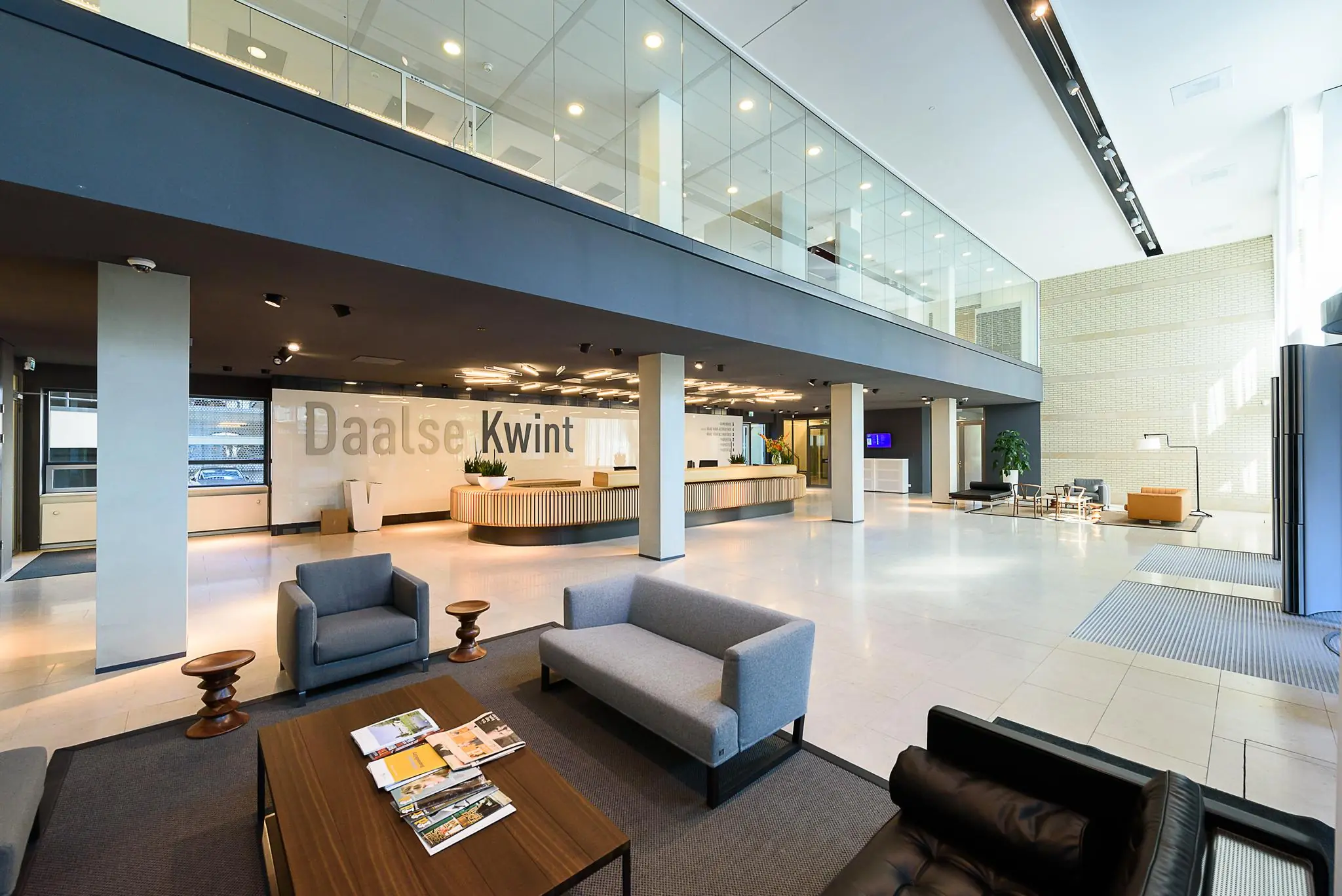 Moderne, ruimtelijke entreehal van het Daalse Kwint-gebouw met balie, zitgedeelte en glazen verdiepingsvloer.