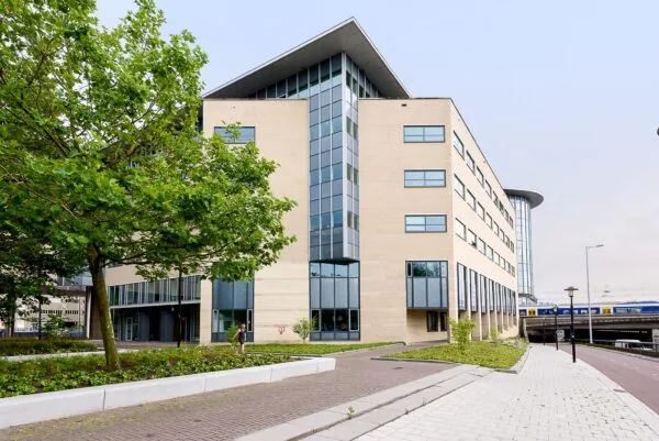 Modern kantoorgebouw aan het Daalseplein in Utrecht met een NS-trein op de achtergrond.