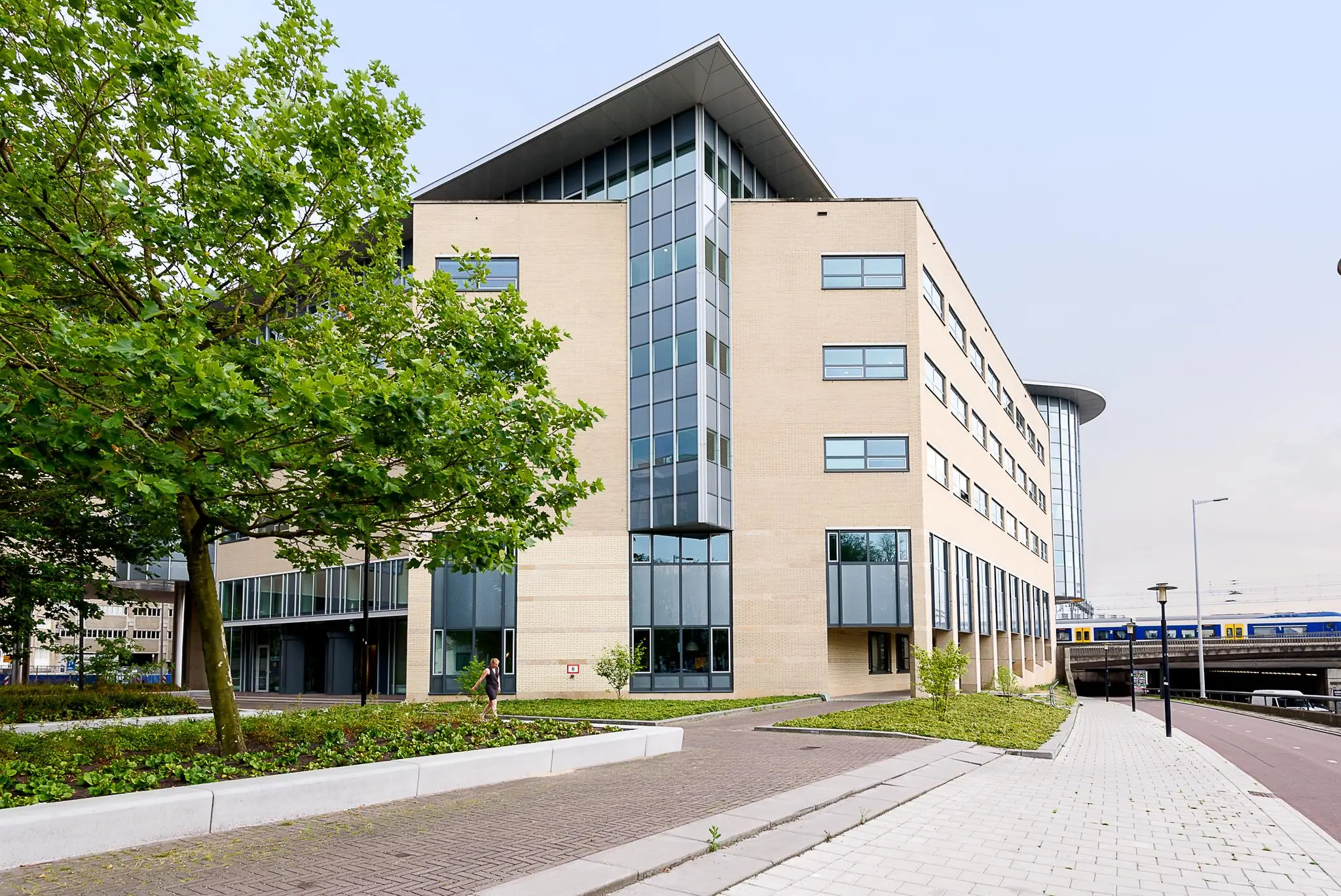 Modern kantoorgebouw aan het Daalseplein in Utrecht met een NS-trein op de achtergrond.
