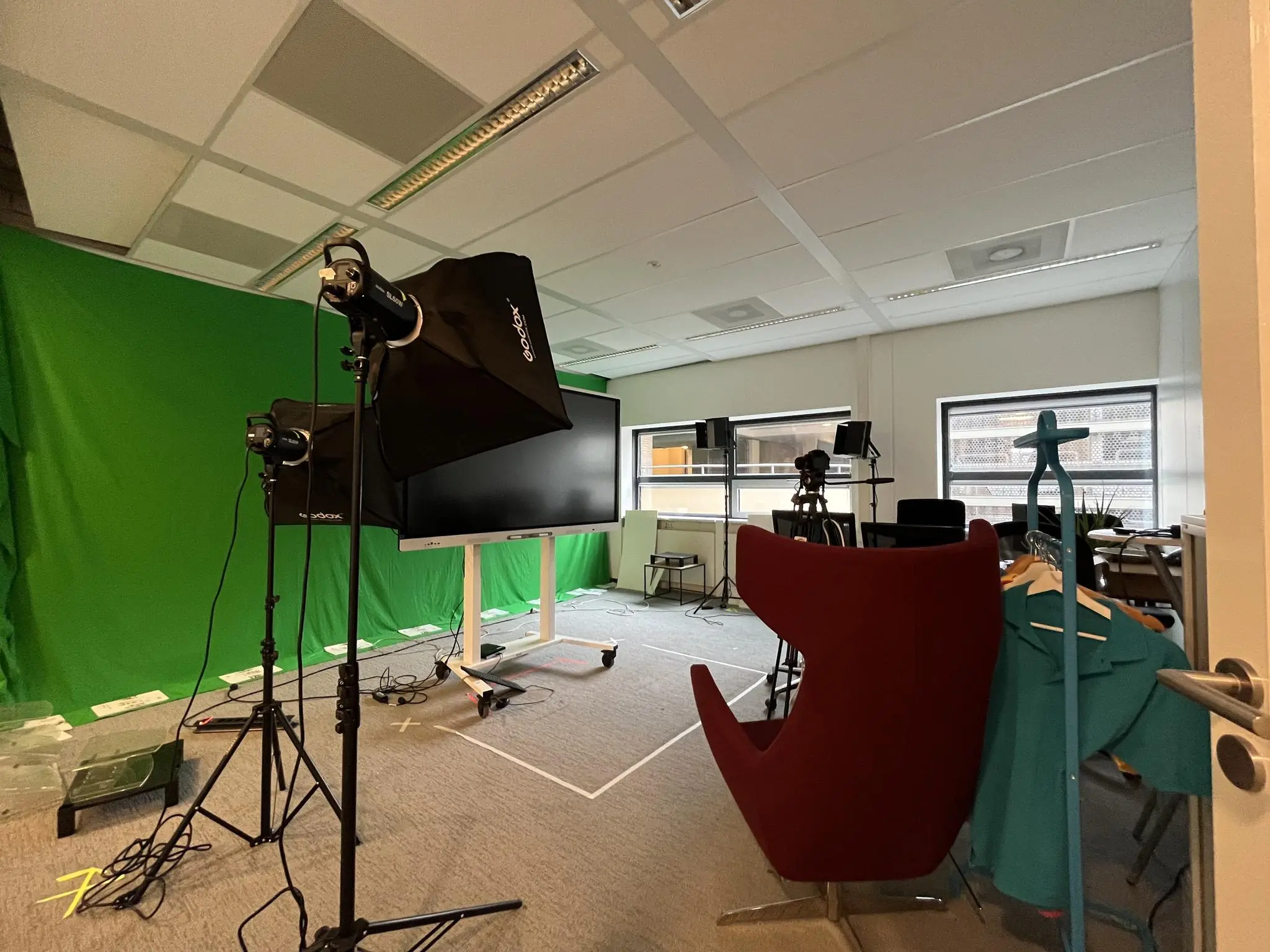 Opnamestudio op het Daalseplein met green screen, verlichting, cameraapparatuur en een grote monitor.
