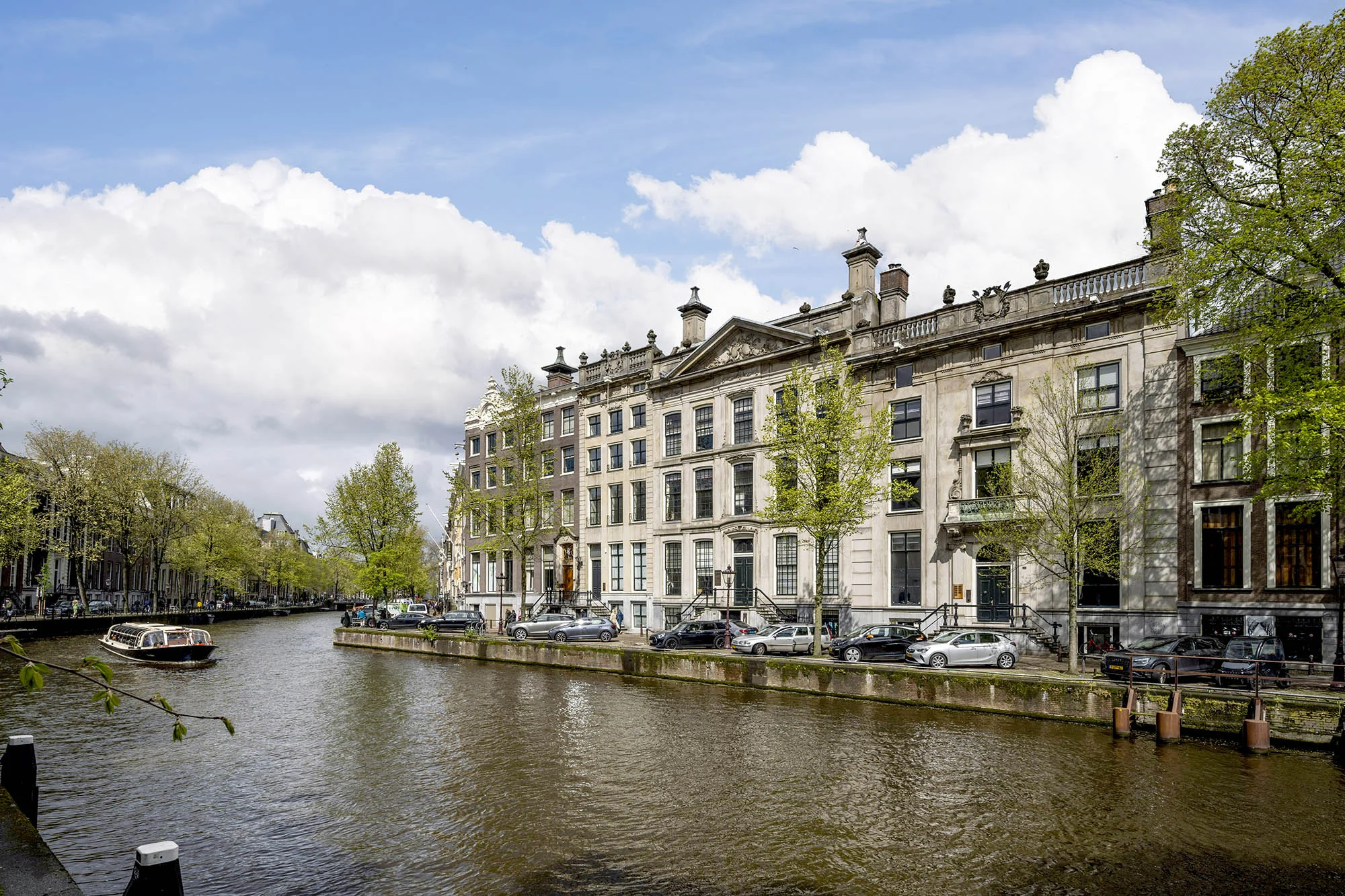 Monumentale grachtenpanden aan de Herengracht in Amsterdam met een rondvaartboot op het water.